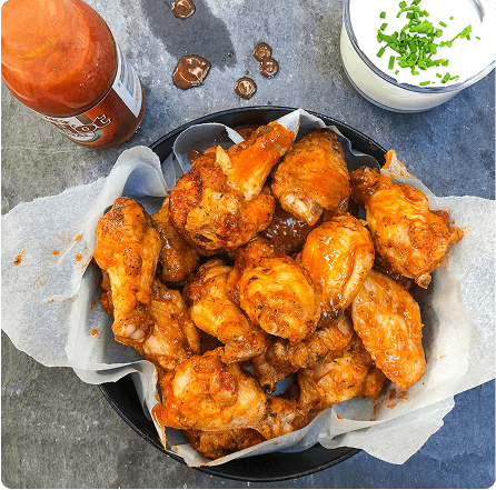 Perfectly cooked buffalo wings served in a basket